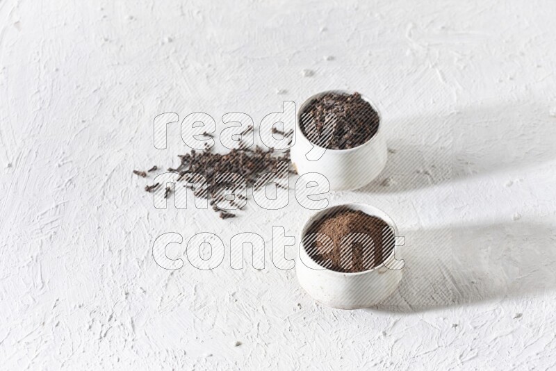 وعاءين من السيراميك بيج اللون، أحدهما مملوء بالقرنفل والآخر مملوء بالبودرة على أرضية بيضاء