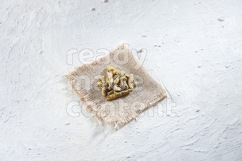 Dried turmeric whole fingers on a piece of burlap on a textured while flooring