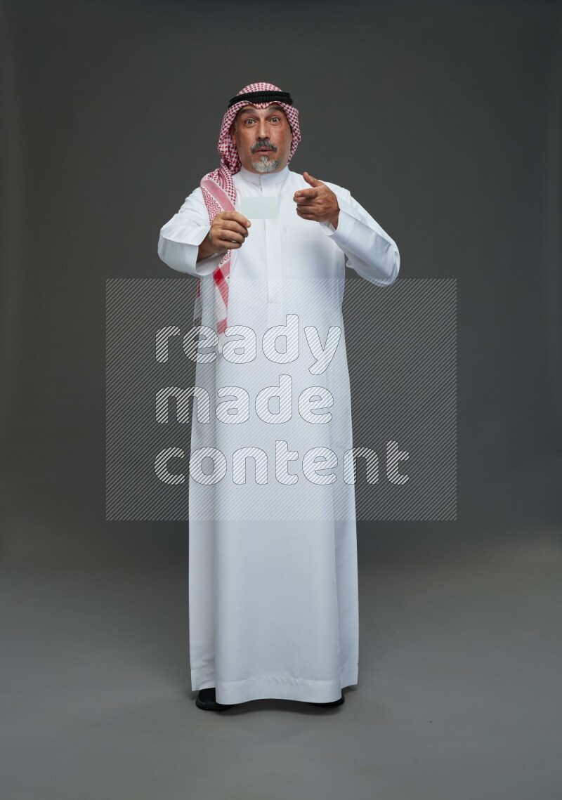 Saudi man with shomag Standing holding ATM card on gray background