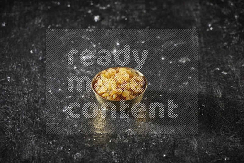 Dried fruits in a metal bowl in a dark setup