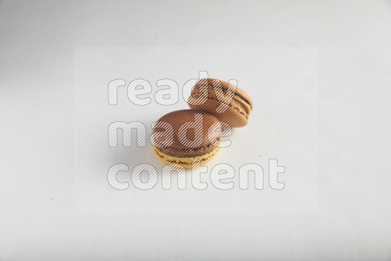 45º Shot of of two assorted Brown Irish Cream, and Yellow, and Brown Chai Latte macarons on white background