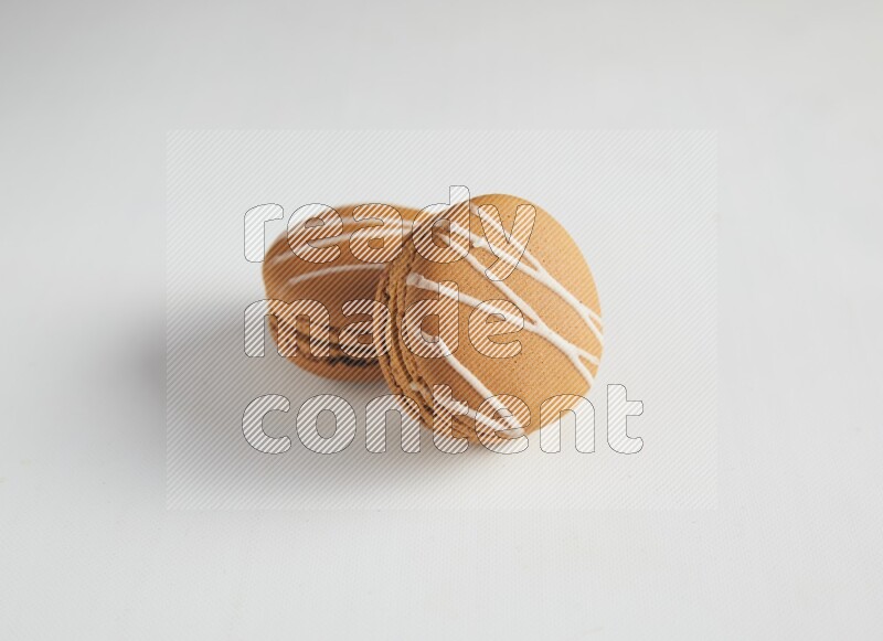 45º Shot of two Brown Irish Cream macarons on white background