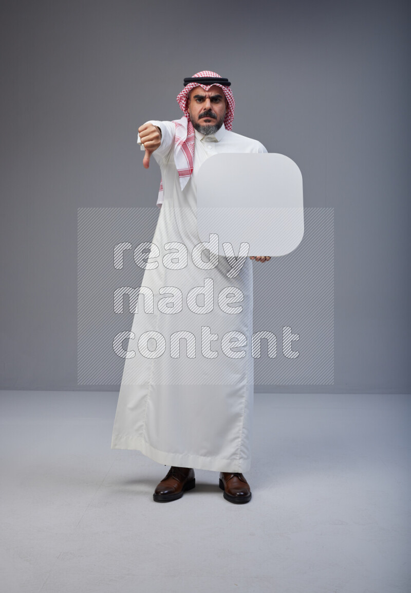 Saudi man Wearing Thob and red Shomag standing holding social media sign on Gray background