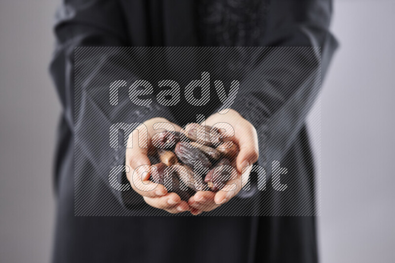 Woman in abaya holding dates in different positions
