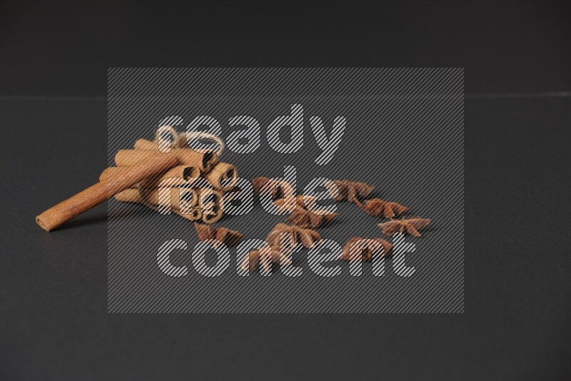 Cinnamon sticks stacked and bounded and star anise on black background