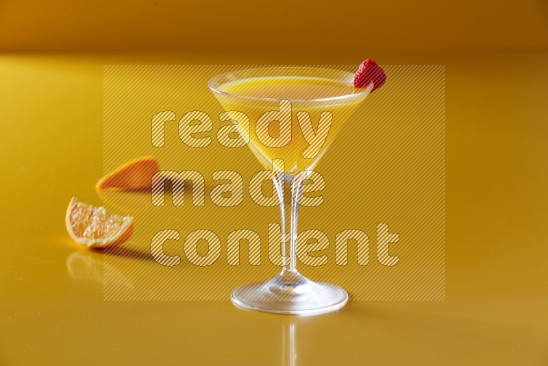 glass of orange juice with berry on yellow background