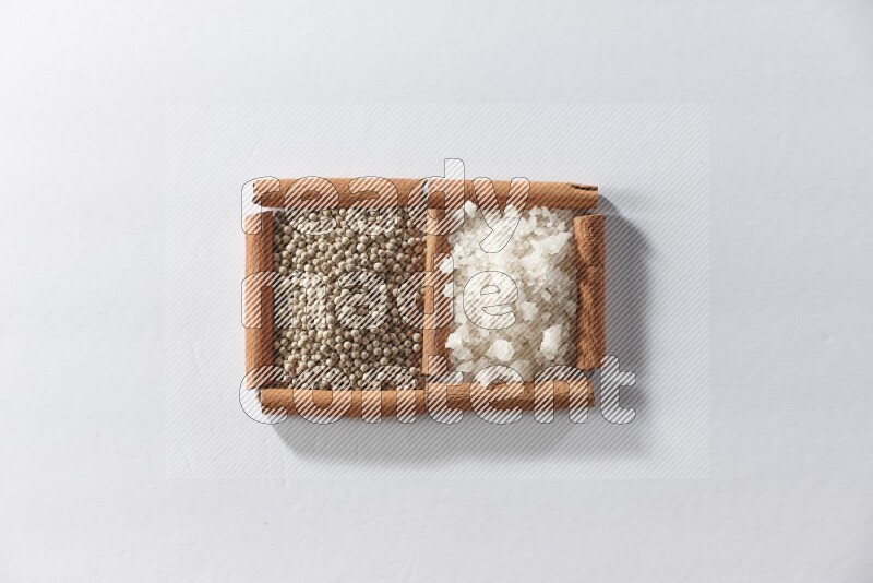 2 squares of cinnamon sticks full of white pepper and white salt on white flooring