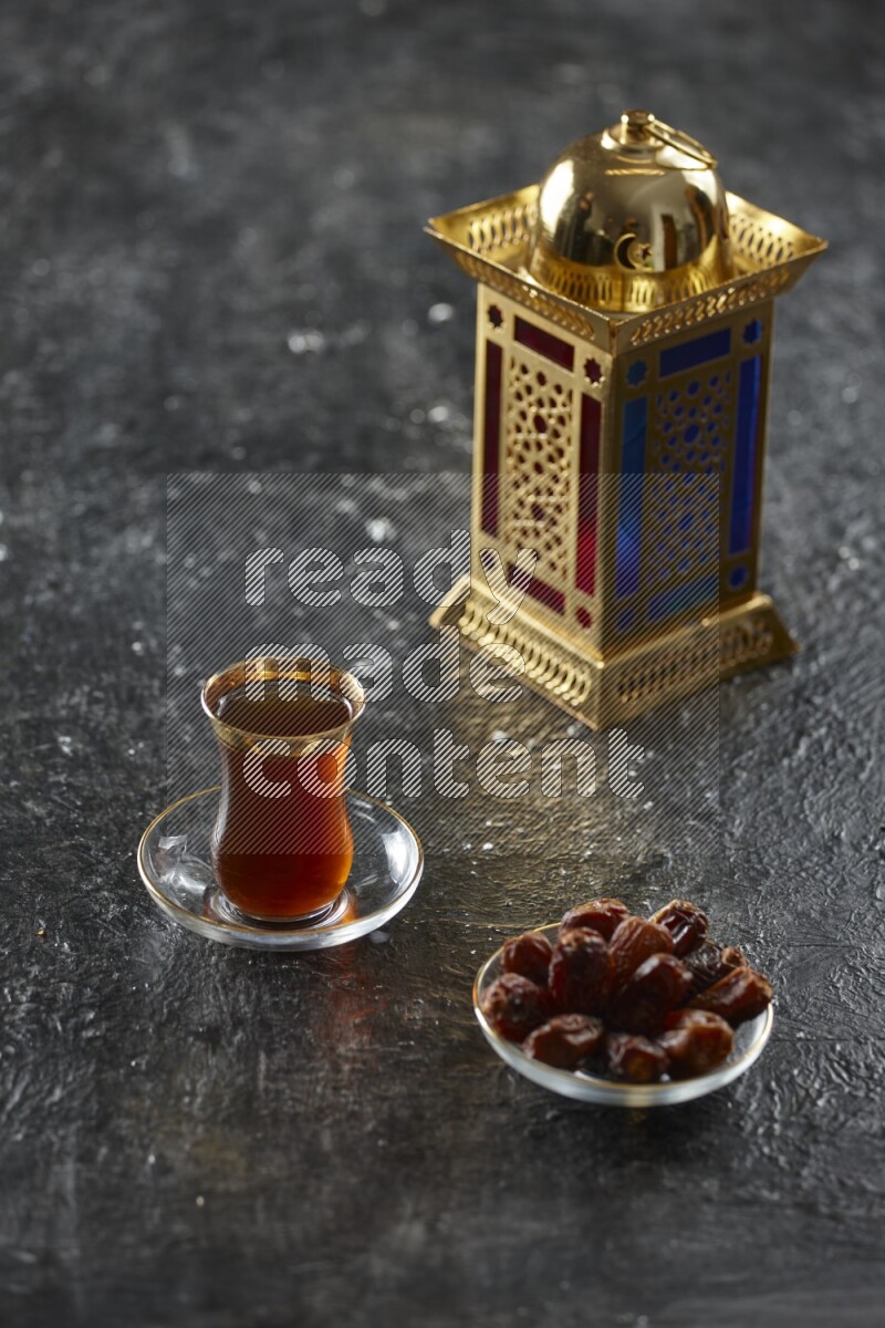 A golden lantern with different drinks, dates, nuts, prayer beads and quran on textured black background