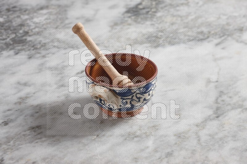 Decorative pottery pot with wooden honey dipper in it on grey marble background