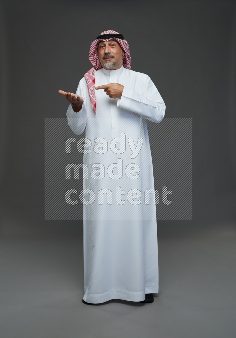 Saudi man with shomag Standing Interacting with the camera on gray background