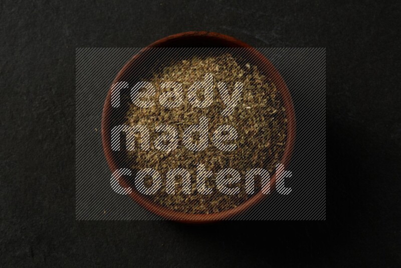 wooden round sauce bowl filled with herbs on grey textured countertop