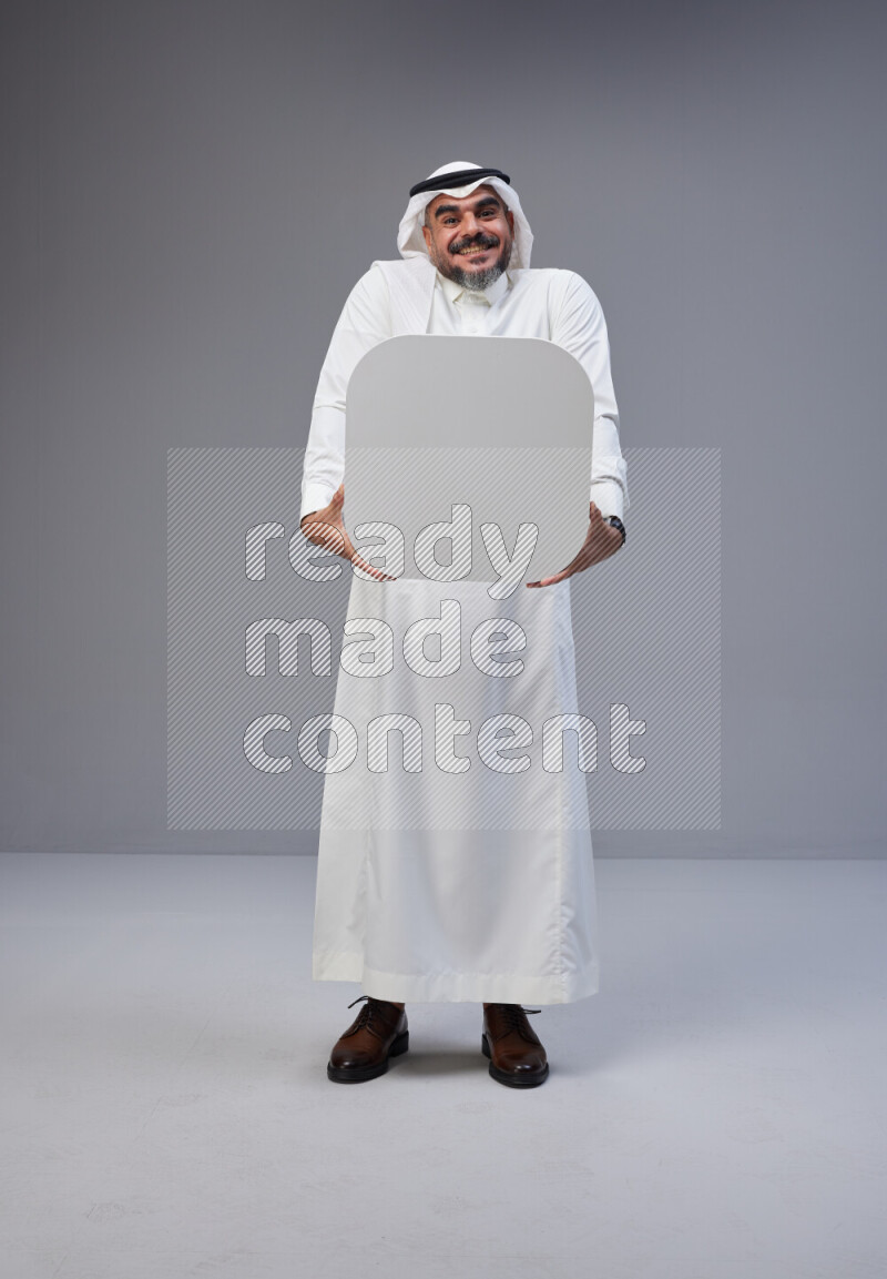 Saudi man Wearing Thob and white Shomag standing holding social media sign on Gray background