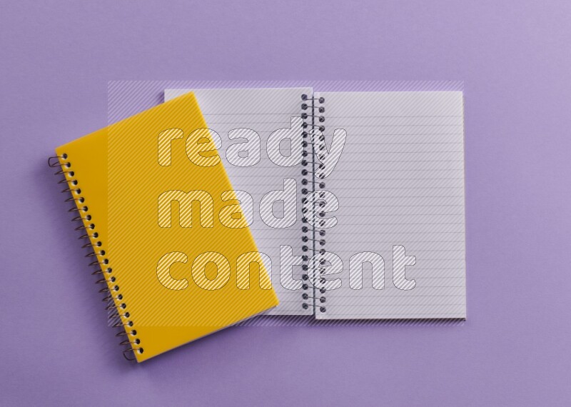 A yellow notebook with school supplies on purple background