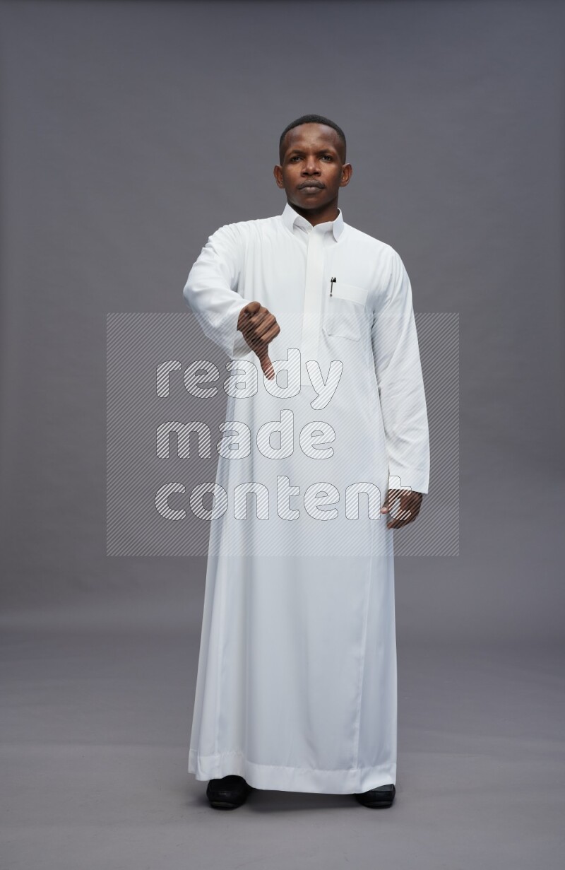 Saudi man wearing thob standing interacting with the camera on gray background