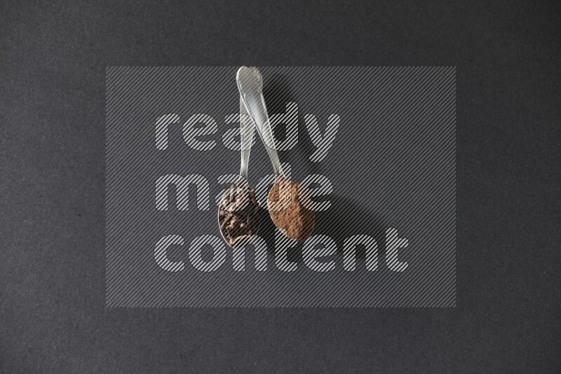 ملعقتان معدنيتان، إحداهما ممتلئة بحبوب القرنفل والأخرى ببودرة القرنفل، على خلفية سوداء