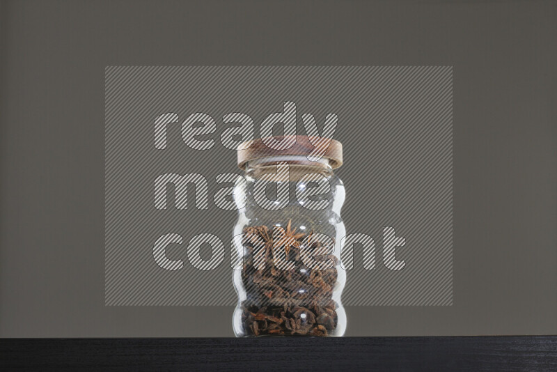Star anise in a glass jar on black background