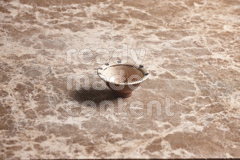 A decorative pottery bowl on beige marble background