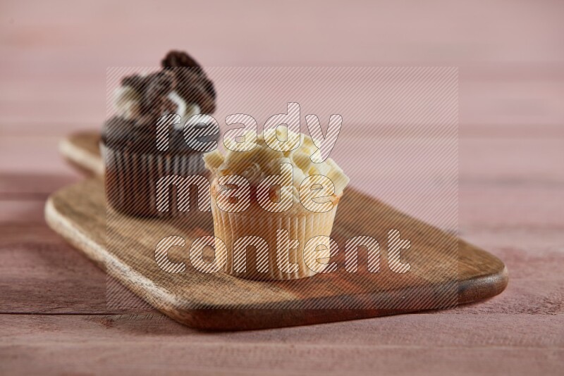 Vanilla mini cupcake topped with white chocolate curls on a wooden board