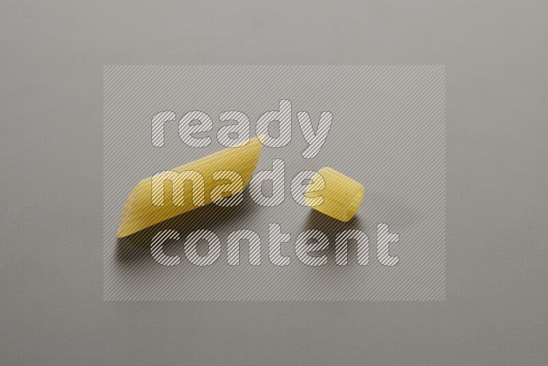 Penne pasta with other types of pasta on grey background
