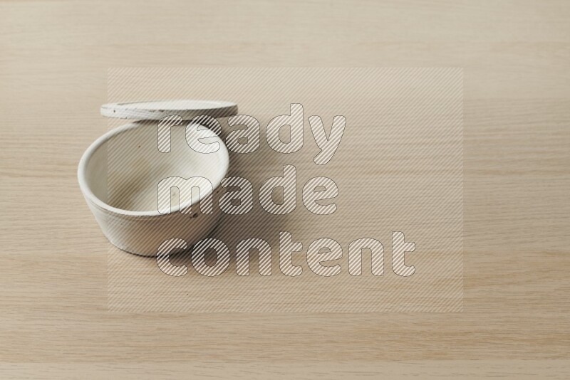 A white pottery bowl on light wooden background