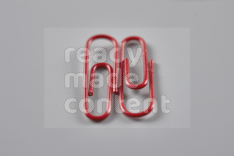 Red paper clips isolated on a grey background