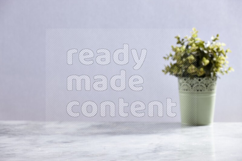 Artificial plant in green decorative pot on grey marble background