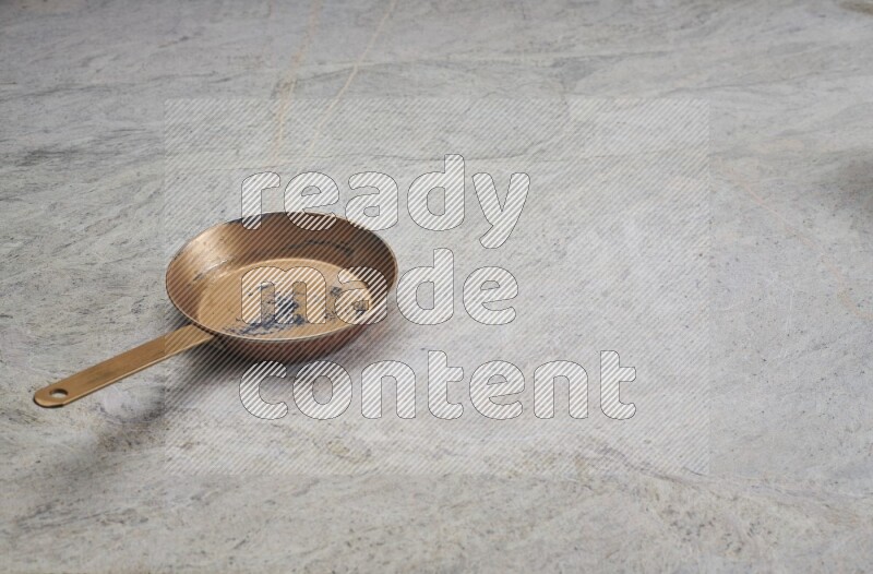 A small copper pan on grey marble background