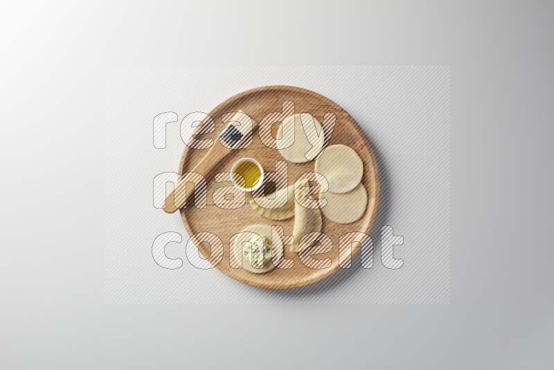 two closed sambosas and one open sambosa filled with cheese while oil with oil brush aside in a wooden dish on a white background
