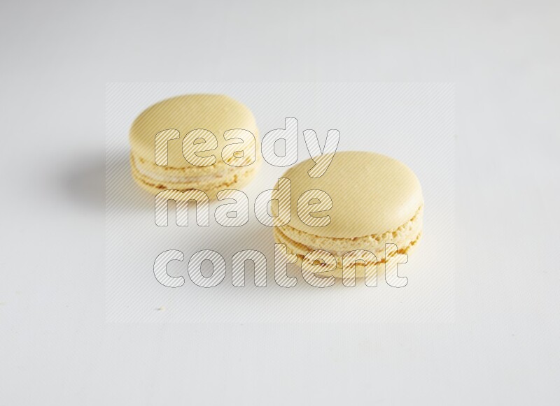 45º Shot of two Yellow Vanilla macarons on white background