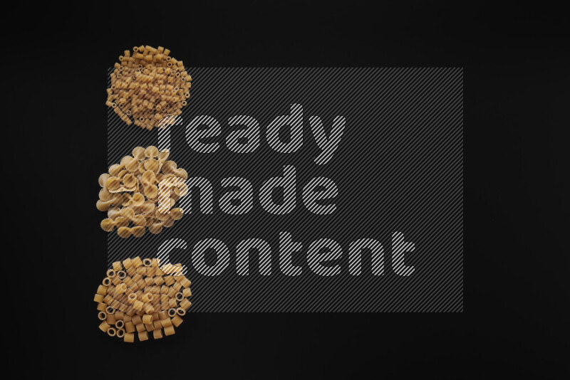 Different pasta types in 3 bunches on black background