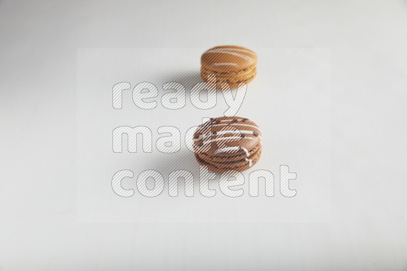 45º Shot of of two assorted Brown Irish Cream, and Brown white Chocolate Caramel macarons on white background