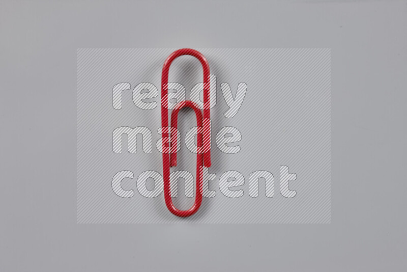 Red paper clips isolated on a grey background