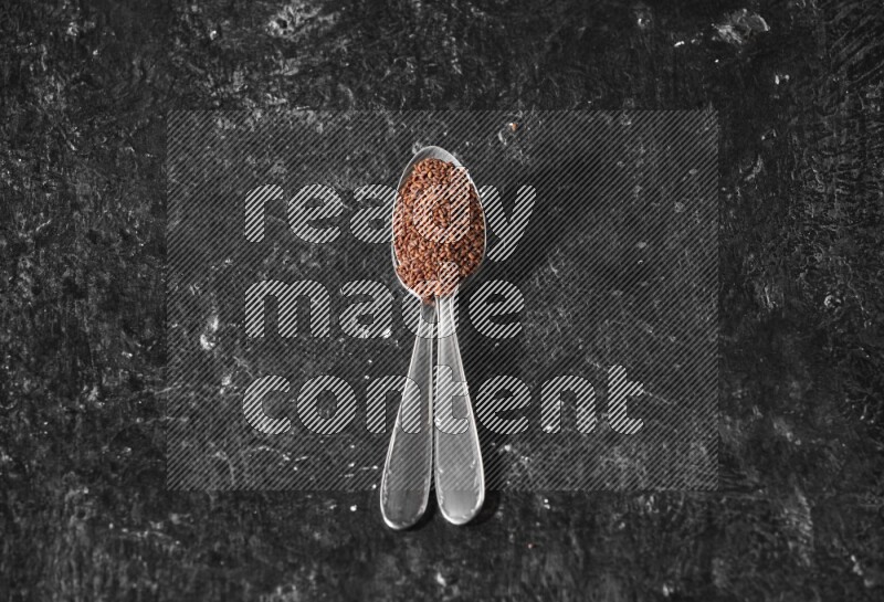 ملعقتان معدنيتان ممتلئتان ببذور حب الرشاد علي خلفية سوداء