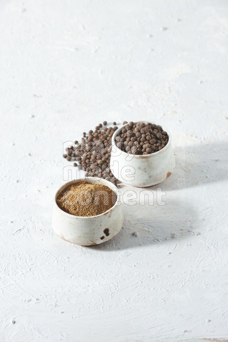 2 beige bowls, one full of powder and the other full of whole balls with balls and powder spreaded on a textured white flooring