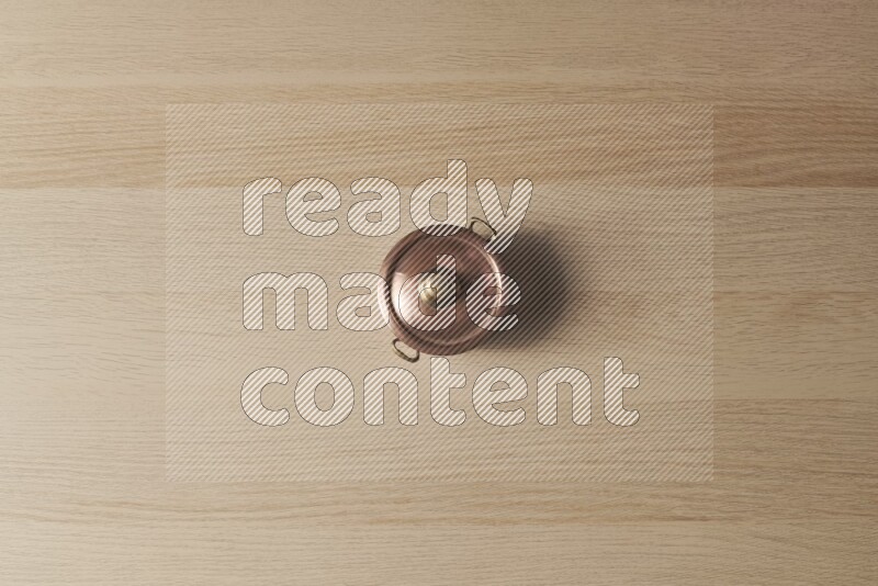 A small copper pot on light wooden background