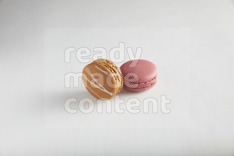 45º Shot of of two assorted Brown Irish Cream, and Pink Raspberry macarons on white background