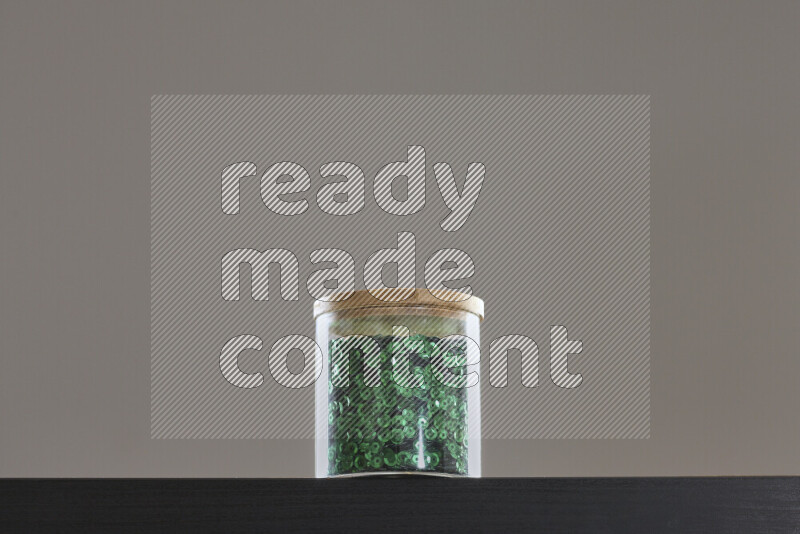 Sequins in a glass jar on black background
