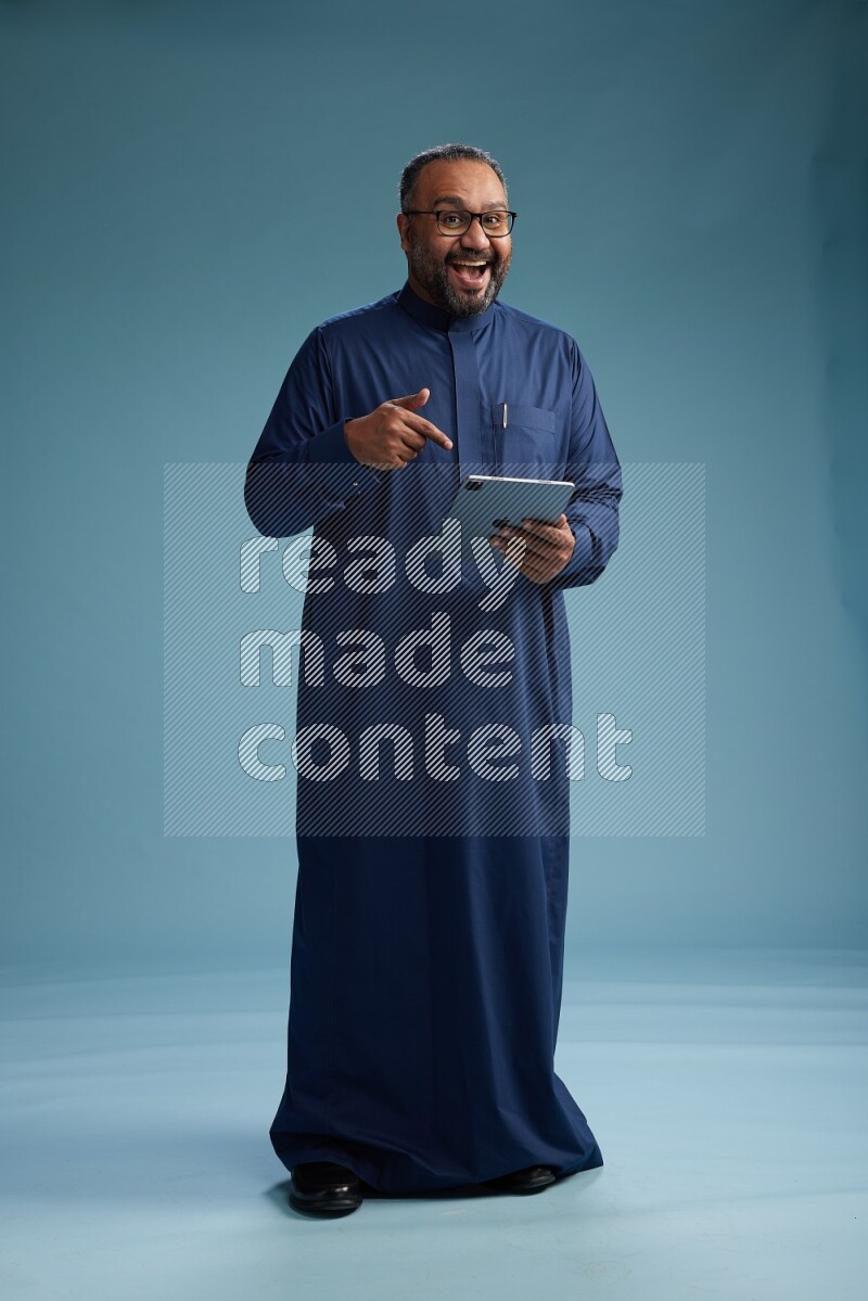 Saudi Man without shimag Standing working on tablet on blue background