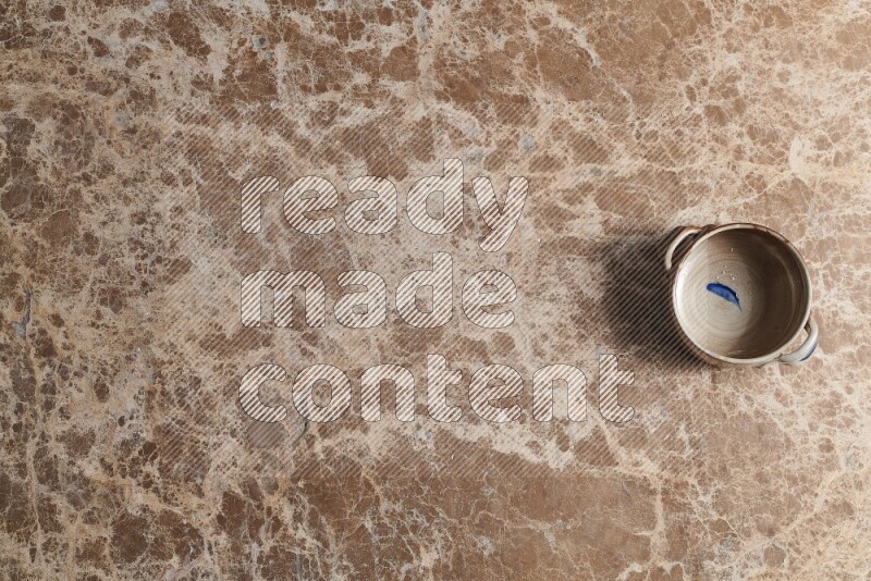 A multicolored pottery bowl on beige marble background