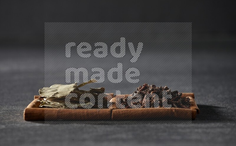 2 squares of cinnamon sticks full of cloves and bay laurel leaves on black flooring
