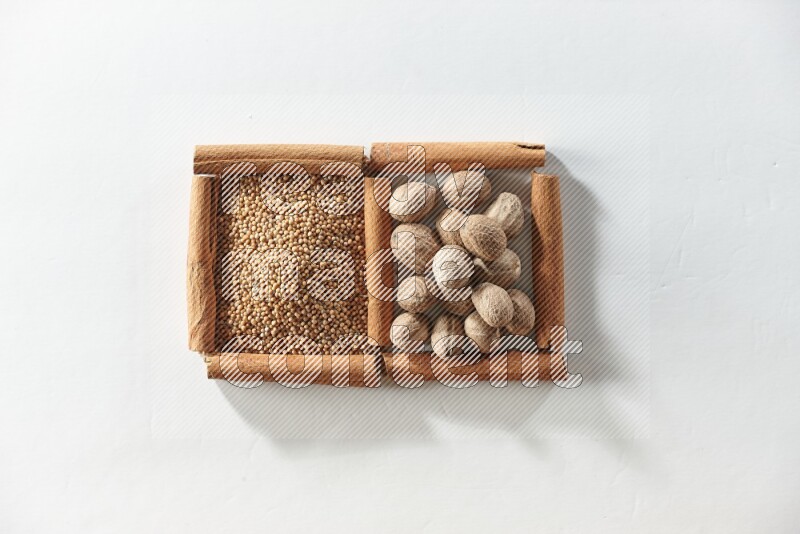 مربعان من أعواد القرفة ممتلئان بحبوب الخردل وجوزة الطيب علي خلفية بيضاء