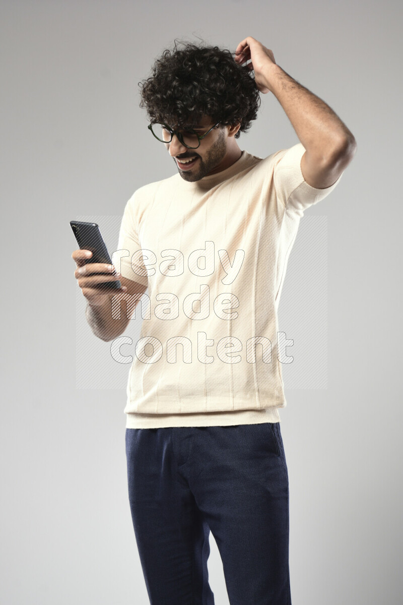 A man wearing casual standing and texting on the phone on white background
