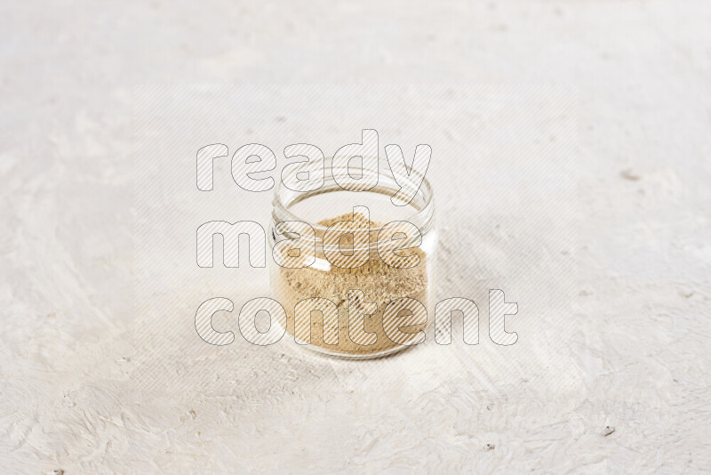 A glass jar full of ground ginger powder on white background