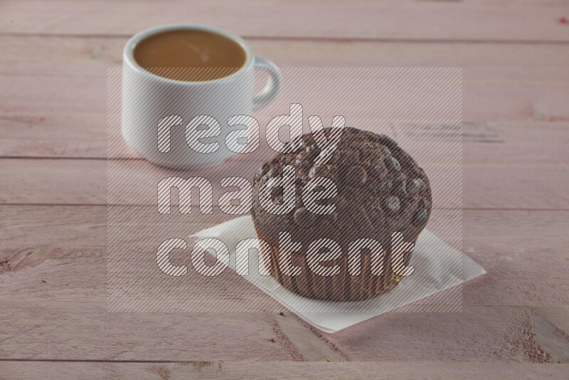 Chocolate cupcake topped with chocolate chips on a wooden pink background