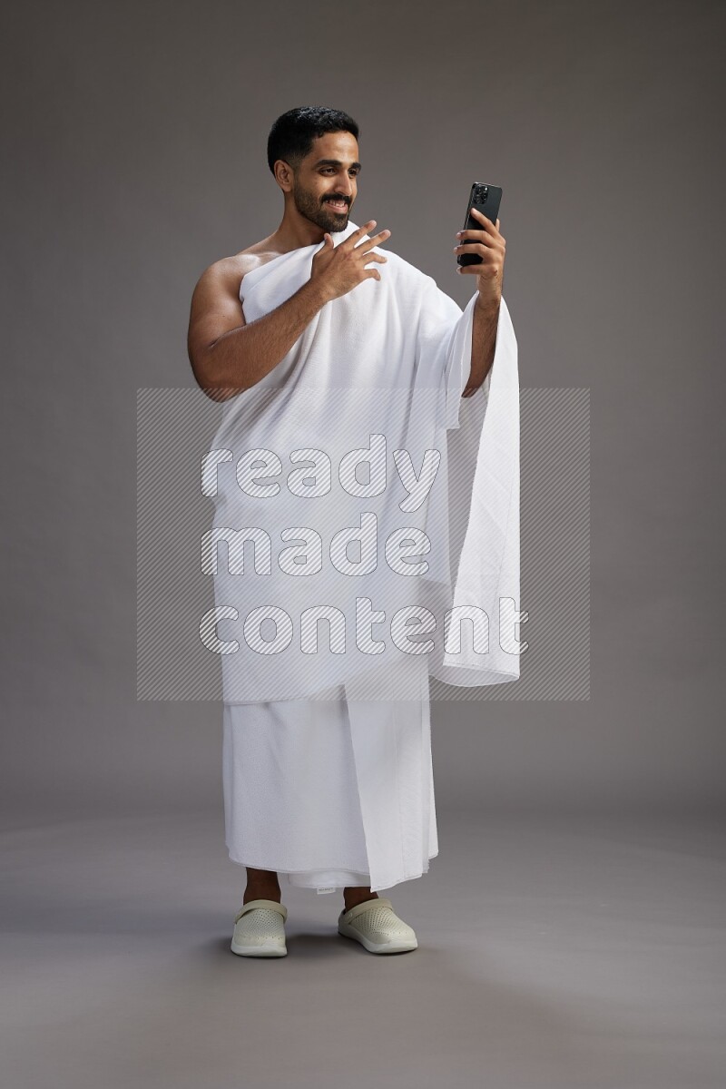 A man wearing Ehram Standing taking selfie on gray background