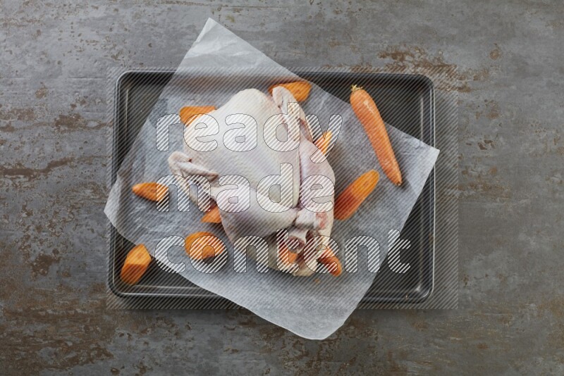whole raw chicken on an oven trey direct on a rustic grey background