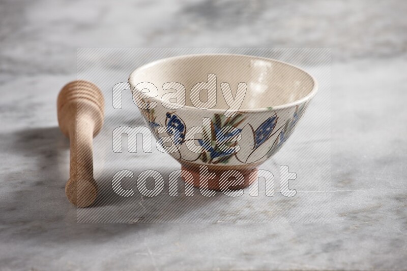 Decorative pottery bowl with wooden honey dipper on the side on grey marble background