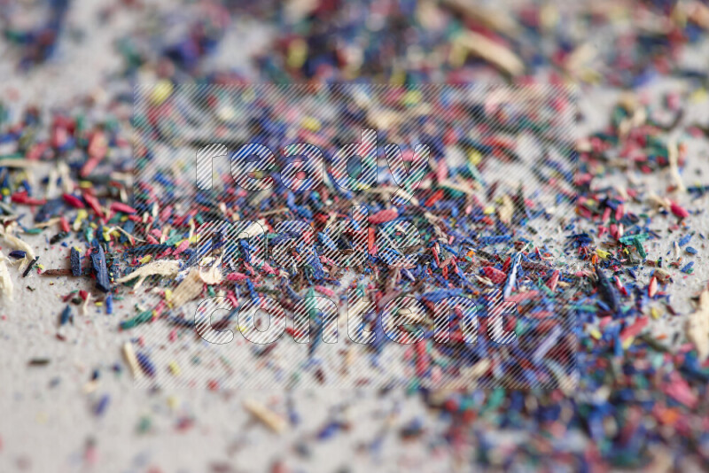 This image showcases a vibrant multicolored pencil shavings scattered on grey background