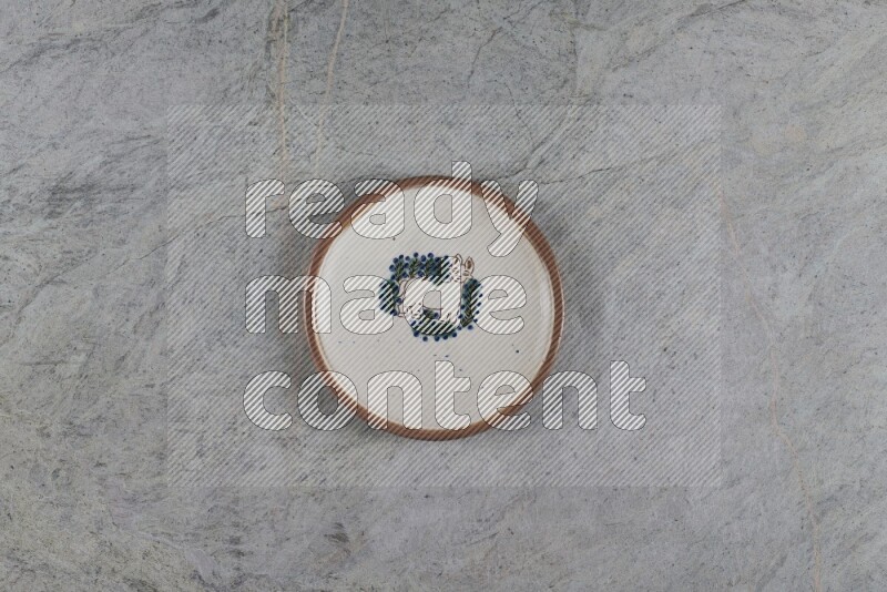 A decorative pottery plate on grey marble background