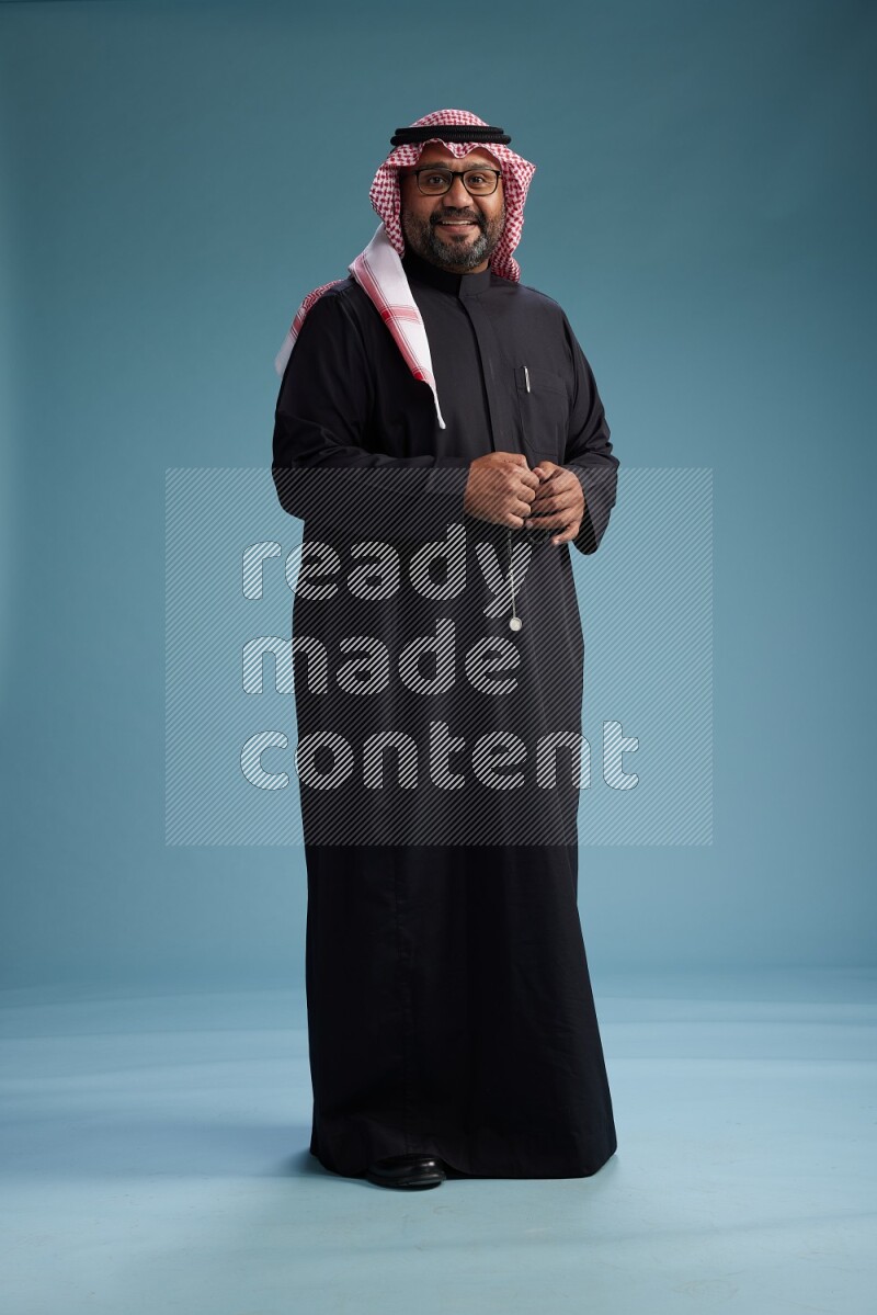 Saudi Man with shimag Standing Interacting with the camera on blue background